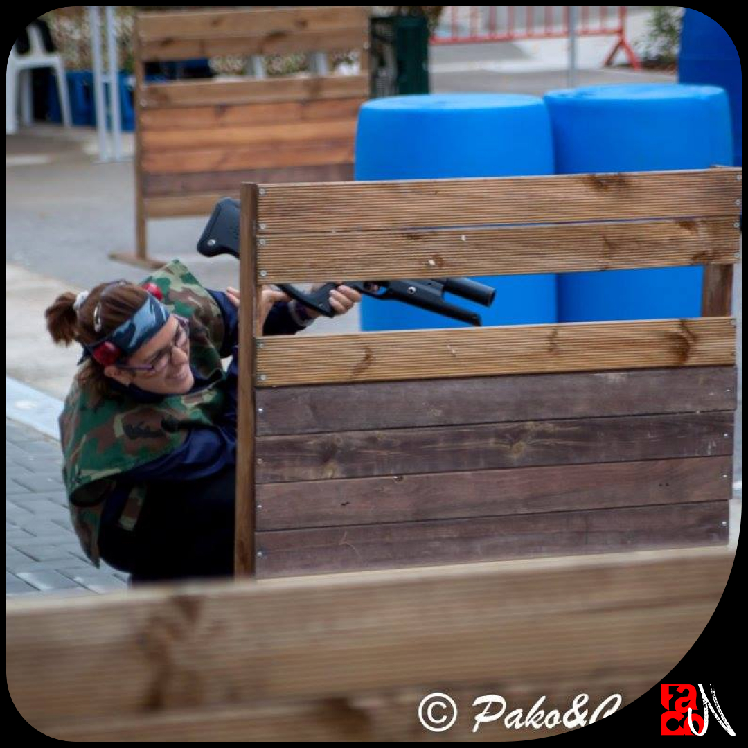 Chica darrere d'una barricada jugant a airsoft